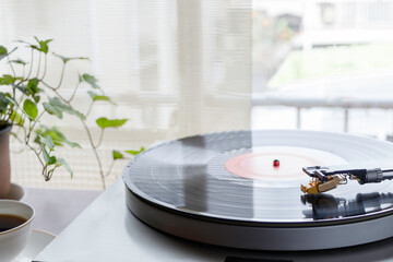 陽が射し込む窓辺のレコードプレイヤーで趣味の音楽を聴く