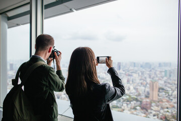 Tourist friends taking photos of Tokyo skyscraper.
