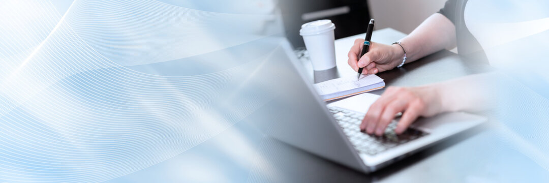 Woman taking notes while using laptop; panoramic banner