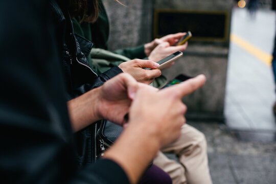 Closeup of friends using their smartphone on the street.