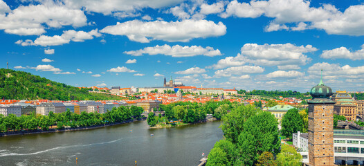 Fototapeta na wymiar Panorama of Prague city historical centre with Prague Castle, St. Vitus Cathedral, Hradcany district, green hills and Vltava river, blue sky. Aerial panoramic view of Prague city, Czech Republic