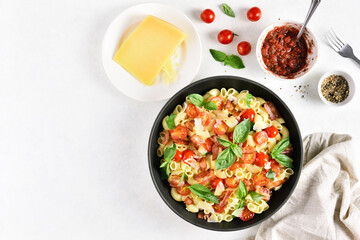 Tomato and bacon pasta with parmesan cheese and basil leaves