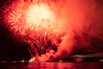 Holiday fireworks above water with reflection on the black sky background