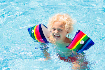 Child in swimming pool. Kid with float armbands.
