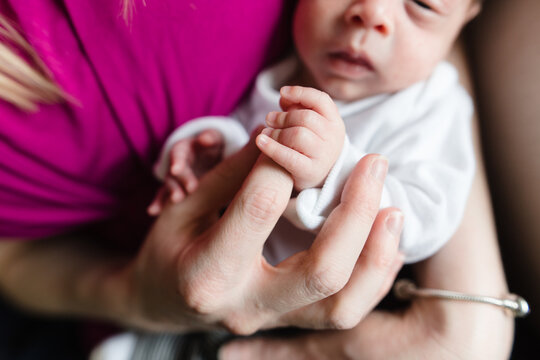 closeup of baby holding moms finger