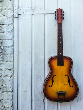 Vintage guitar hanging against a wall with copyspace