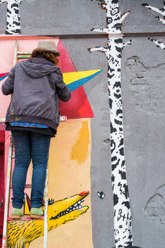 Female Graffiti Artist Writing On Wall