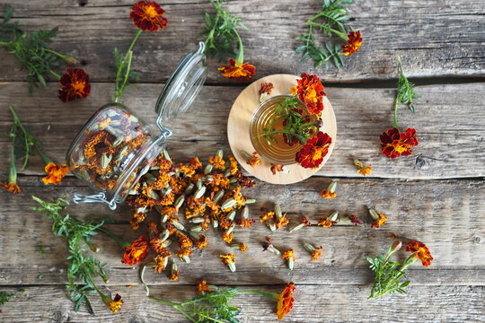 Dried marigold flowers with medicinal herbal tea on a wooden background. The use of flowers Chernobrovtsy or Mary is Gold in folk alternative medicine.