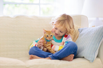 Child playing with cat. Kid and kitten.