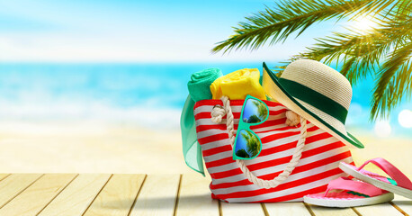 Beach bag, flip flops, hat and sunglasses on a tropical beach.