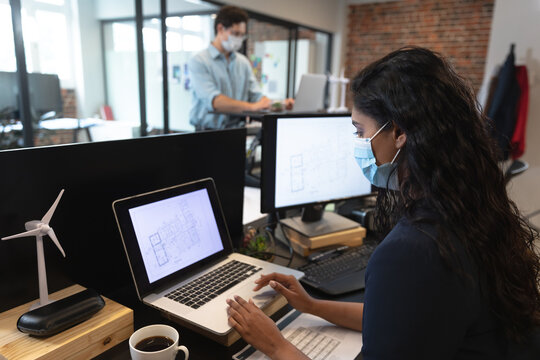 Woman wearing face mask using laptop at office