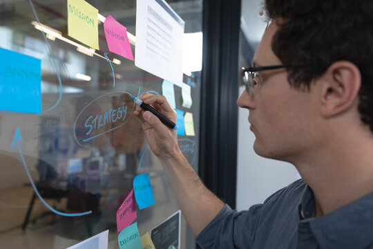 Man writing on glass board at office