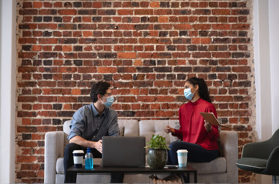 Man and woman wearing face mask discussing in office