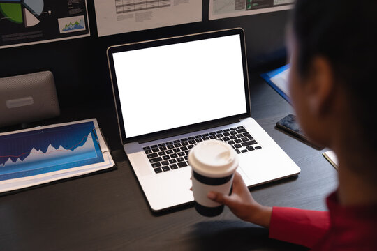 Woman holding coffee cup using laptop at office