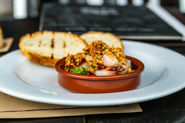 lunch sea food, shrimps with a tremolata delicious and fragrant in a clay plate stands against the background of toasts