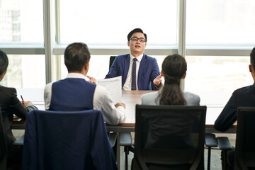 young asian job candidate talking big during a group interview