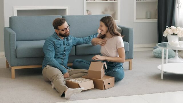 Happy man giving gift boxes to pretty young woman at home. Happy thankful excited female smiling and hugging her boyfriend. Gift and surprise for birthday. Joyful wife and husband, real relationships