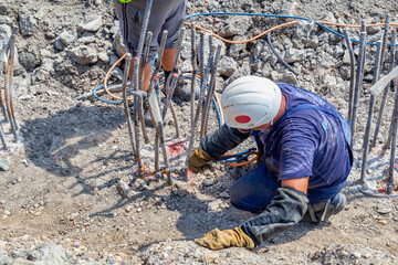 Workers cutting concrete reinforcing steel rods with torch