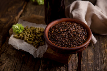 ingredients for making beer. Hops, dark malt in a bowl on a wooden background. Background image