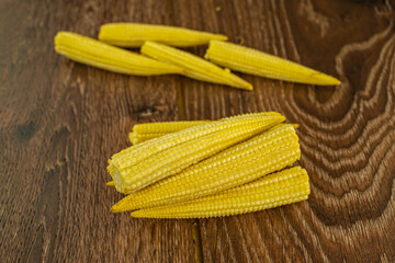 set of mini ears of corn yellow closeup on a dark brown board
