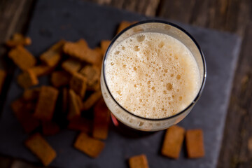 Beer foam, dark beer in a glass. croutons are scattered on the table, top view