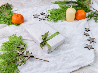 Geschenk zu Weihnachten mit Tannengrün, Mandarine, Kerze, Sternen und Kerze
