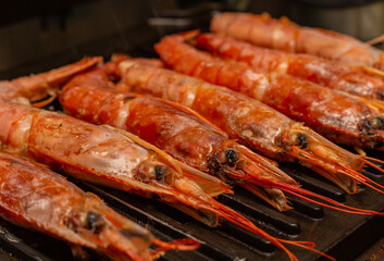 set of large langoustines with their heads stacked in a row on the grill