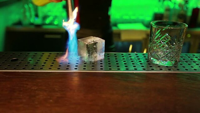The bartender makes a seal on a large ice cube. Slow motion.