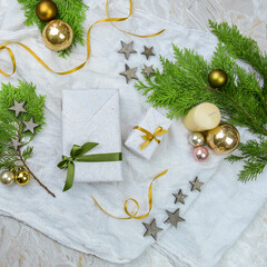 Geschenk zu Weihnachten mit Tannengrün, goldene Christbaumkugeln, Kerze, Sternen und Kerze