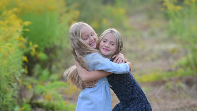 Two happy girls are playing and hugging in the park. Happy family kid and sister lifestyle. Couple of happy children
