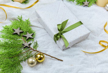 Geschenk zu Weihnachten mit Tannengrün, goldene Christbaumkugeln, Kerze, Sternen und Kerze