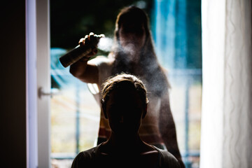 Ein Haarstylist Sprüht die Frisur einer Frau als Finish mit Haarspray ein