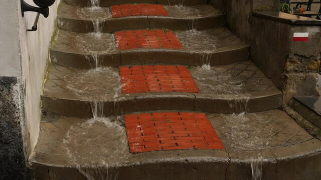 Extreme rain, water pouring down stairs in Italian village. Close up.
