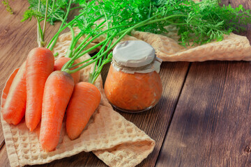 Canned carrot sauce salad with garlic and horseradish in a jar with fresh vegetables, recipe homemade diet vitamin preserves, chopped grated caviar dressing for soup on natural wooden table background