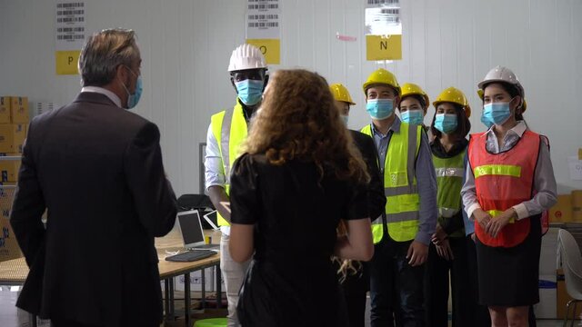 Executive business man and manager wearing face protective medical mask meeting in large warehouse explain new normal policy protect coronavirus or covid-19 outbreak pandemic   . Owner visits factory