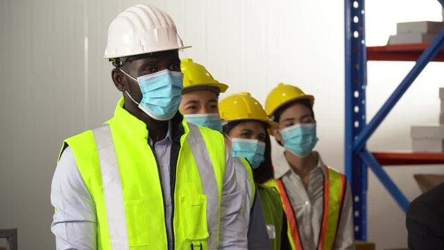 Group of diverse workers wearing face protective medical mask  standing in meeting at warehouse  Listening new normal policy protect coronavirus or covid-19 outbreak pandemic and social distancing