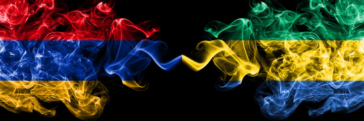 Armenia vs Gabon, Gabonese smoky mystic flags placed side by side. Thick colored silky abstract smoke flags