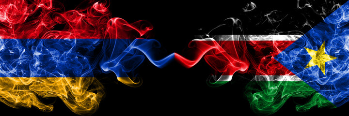 Armenia vs South Sudan smoky mystic flags placed side by side. Thick colored silky abstract smoke flags