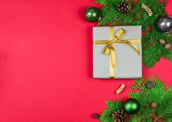 Weihnachtsdekoration auf rotem Hintergrund mit Tannengrün, Geschenk und Weihnachtskugel