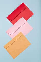 Three colored envelopes on blue background top view