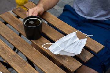Man is  holding coffee cup in his hand with mask