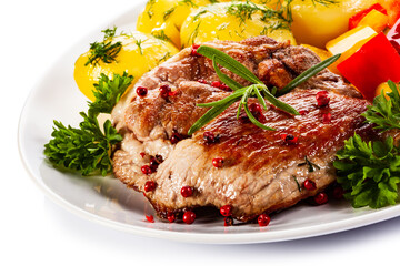 Grilled steak with boiled potatoes and vegetables on white background
