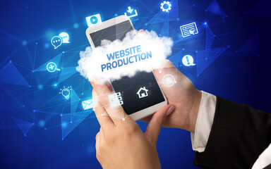 Female hand holding smartphone with WEBSITE PRODUCTION inscription, cloud technology concept