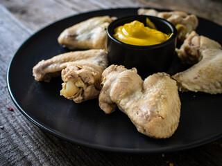 Boiled chicken wings with mustard on wooden board
