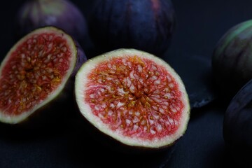 Macro closeup of two isolated fresh ripe sliced halves fig fruits wioth black slate stone background