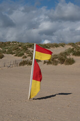 Lifeguard flag blowing in the strong winds on Camber Sands beach