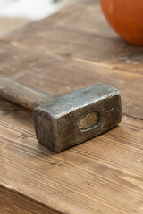 old metal and heavy hammer builder's work tool or forge on wooden table