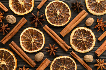 Ingredients for mulled wine. Top view of dried orange slices, cinnamon sticks, anise, and nutmeg on a dark wooden background. Close-up, Flat lay