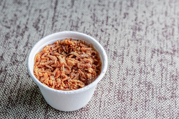 dried and caramelized garlic crushed in a white paper cup