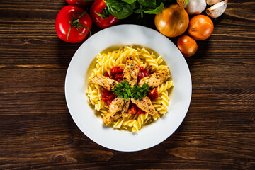 Chicken ragout with fusilli on wooden table
